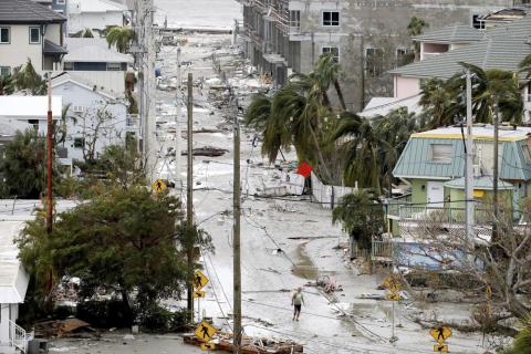 A man walks through a street among damaged homes and businesses and debris in Fort Myers Beach, Fla., on Thursday, Sep 29, 2022, following Hurricane Ian. (Douglas R. Clifford/Tampa Bay Times via AP)