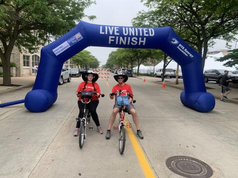 2 cyclists wearing Live United shirts pose at the starting line. 